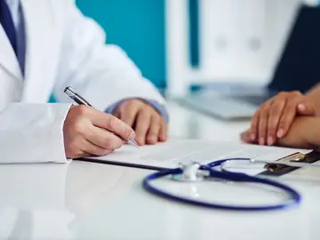 Un médico firma unos documentos Un médico firma unos documentos
