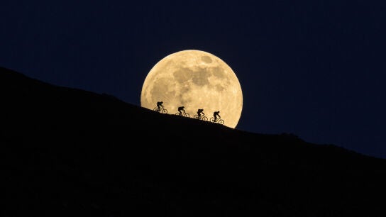 Ciclistas delante de la luna llena