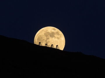 Ciclistas delante de la luna llena