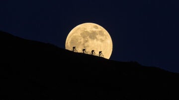 Ciclistas delante de la luna llena