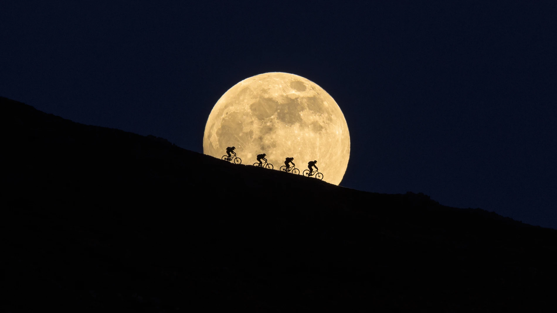 Ciclistas delante de la luna llena Ciclistas delante de la luna llena