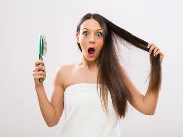 Mujer sorprendida al cepillarse el pelo Mujer sorprendida al cepillarse el pelo