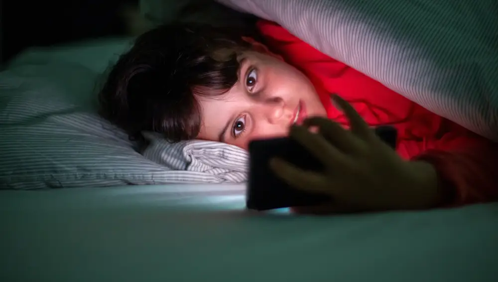 Niño con el móvil en la cama