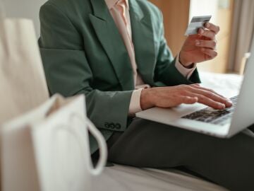 Persona con tarjeta de crédito en la mano y un ordenador