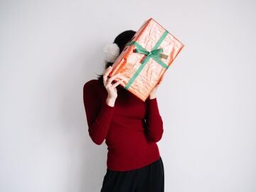 Mujer que esconde su rostro tras un regalo