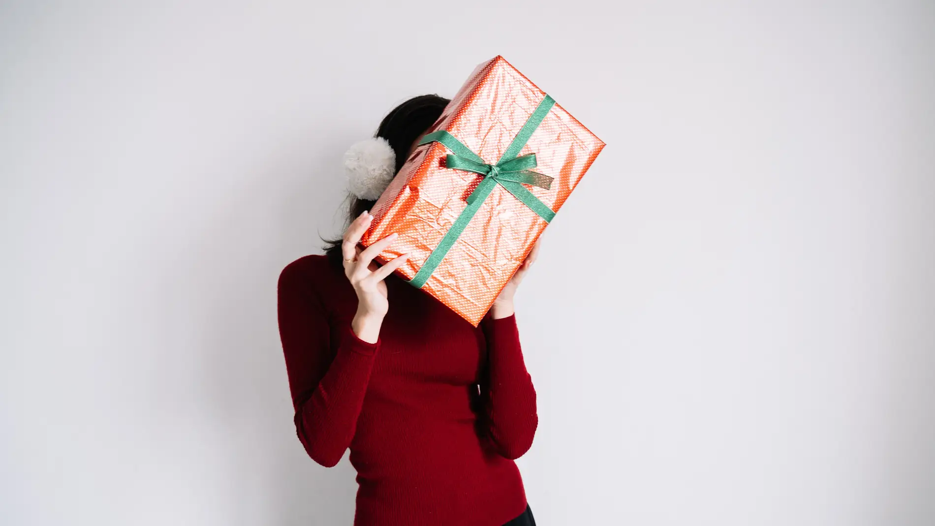Mujer que esconde su rostro tras un regalo