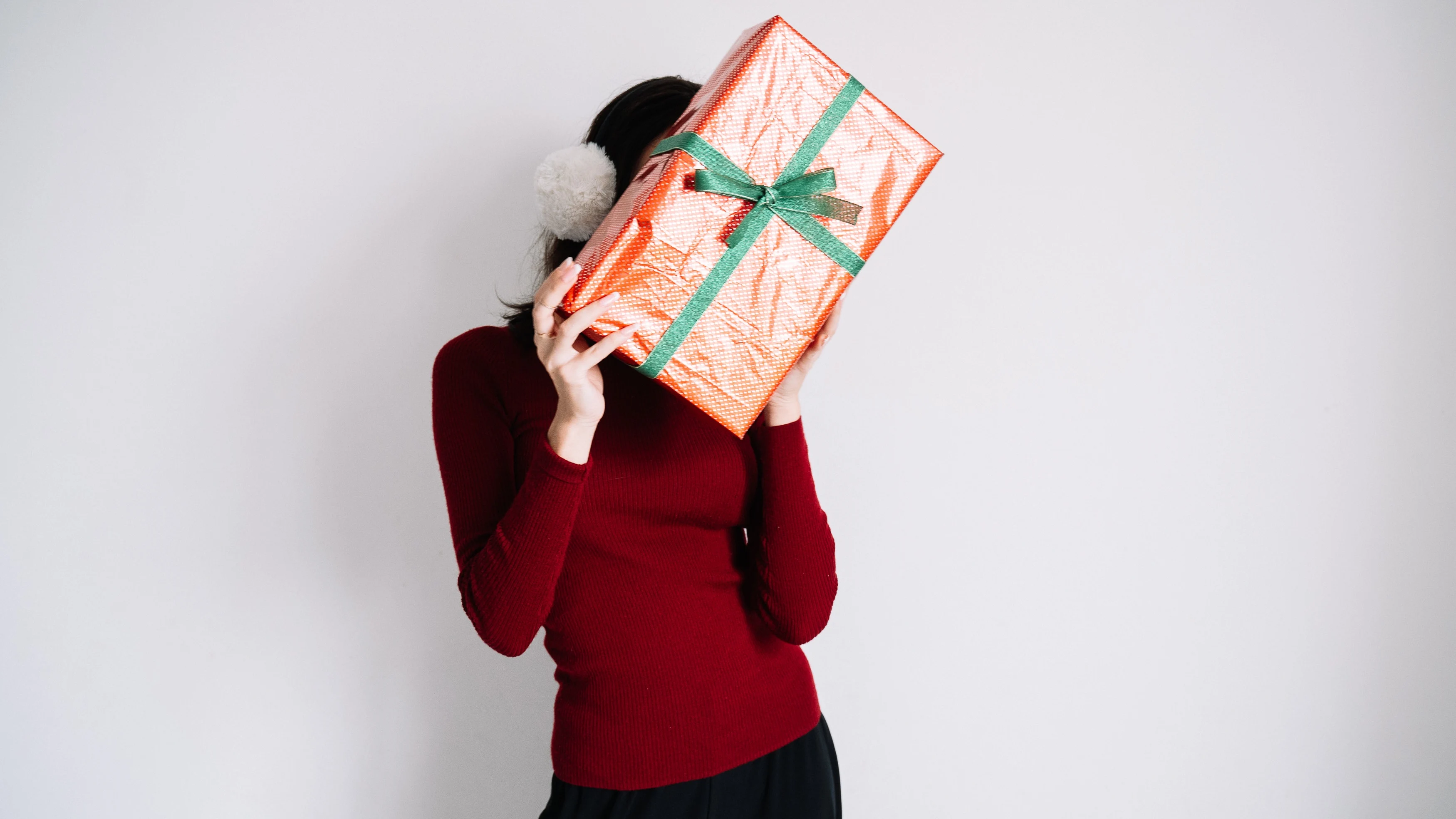Mujer que esconde su rostro tras un regalo Mujer que esconde su rostro tras un regalo