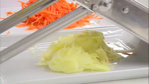 Corta las patatas y la zanahoria con una mandolina Corta las patatas y la zanahoria con una mandolina