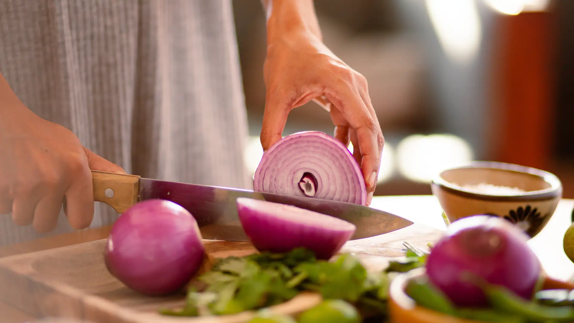 Una persona cortando cebolla en la cocina.