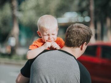 Niño enfadado en brazos de su padre