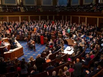 Representantes republicanos de pie y la mayoría de los demócratas permanecen sentados en la Cámara de Representantes de EEUU