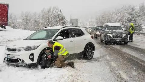 Imagen de recurso de un hombre colocando las cadenas a su coche en la nieve Imagen de recurso de un hombre colocando las cadenas a su coche en la nieve