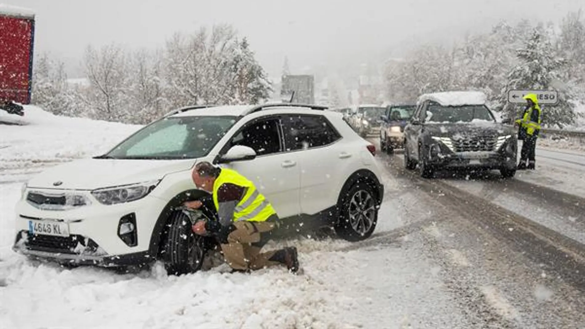 Imagen de recurso de un hombre colocando las cadenas a su coche en la nieve