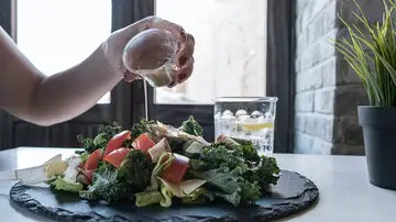 Primer plano de mano echando vinagreta a una ensalada Primer plano de mano echando vinagreta a una ensalada