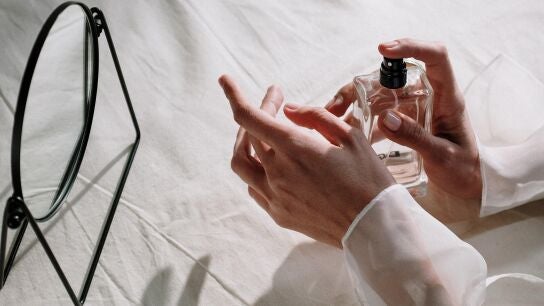 Primer plano de las manos de una mujer aplic&aacute;ndose perfume