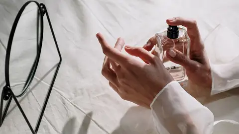 Primer plano de las manos de una mujer aplicándose perfume Primer plano de las manos de una mujer aplicándose perfume