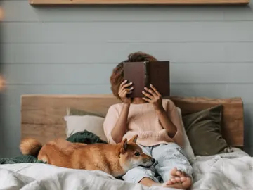 Una mujer junto a su perro en la cama. Una mujer junto a su perro en la cama.