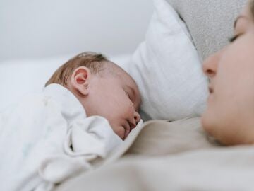 Un bebé duerme junto a su madre
