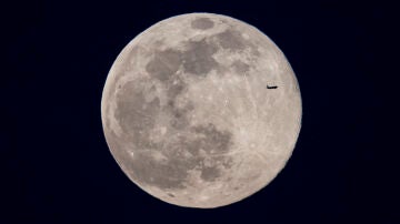 Un avión pasa por delante de la luna llena, este domingo en Madrid. Es la denominada luna llena de nieve.