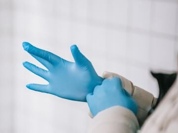 Imagen de un sanitario poniéndose los guantes