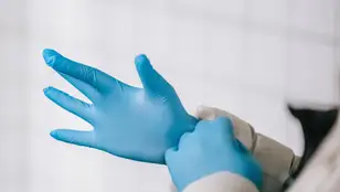 Imagen de un sanitario poniéndose los guantes