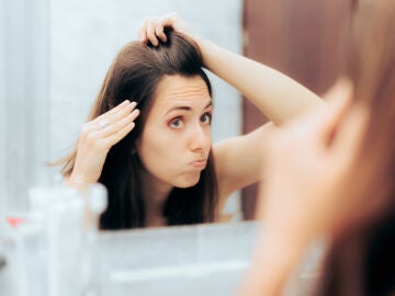 Chica mirándose el pelo en el espejo haciendo una mueca
