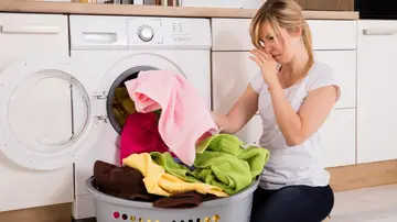 Mujer oliendo ropa que huele mal