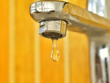Imagen de una gota de agua saliendo del grifo Imagen de una gota de agua saliendo del grifo