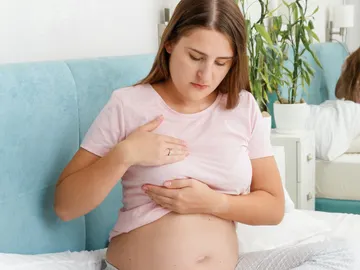 Mujer embarazada tocándose el pecho Mujer embarazada tocándose el pecho