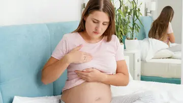 Mujer embarazada tocándose el pecho