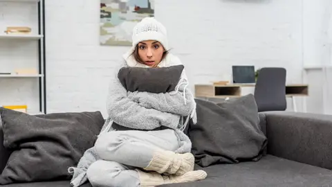 Persona muy abrigada sentada en un sofá Persona muy abrigada sentada en un sofá