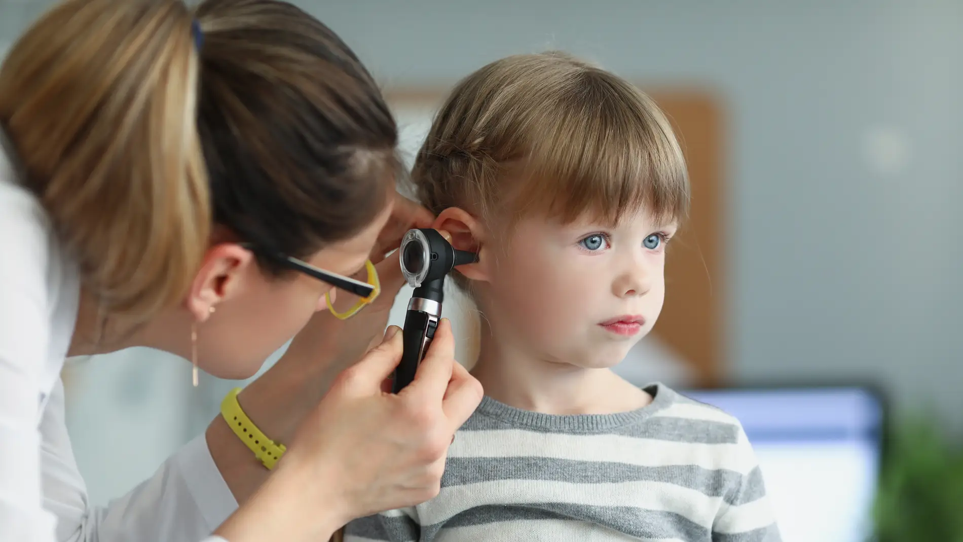 Una pediatra revisa el oído de una niña
