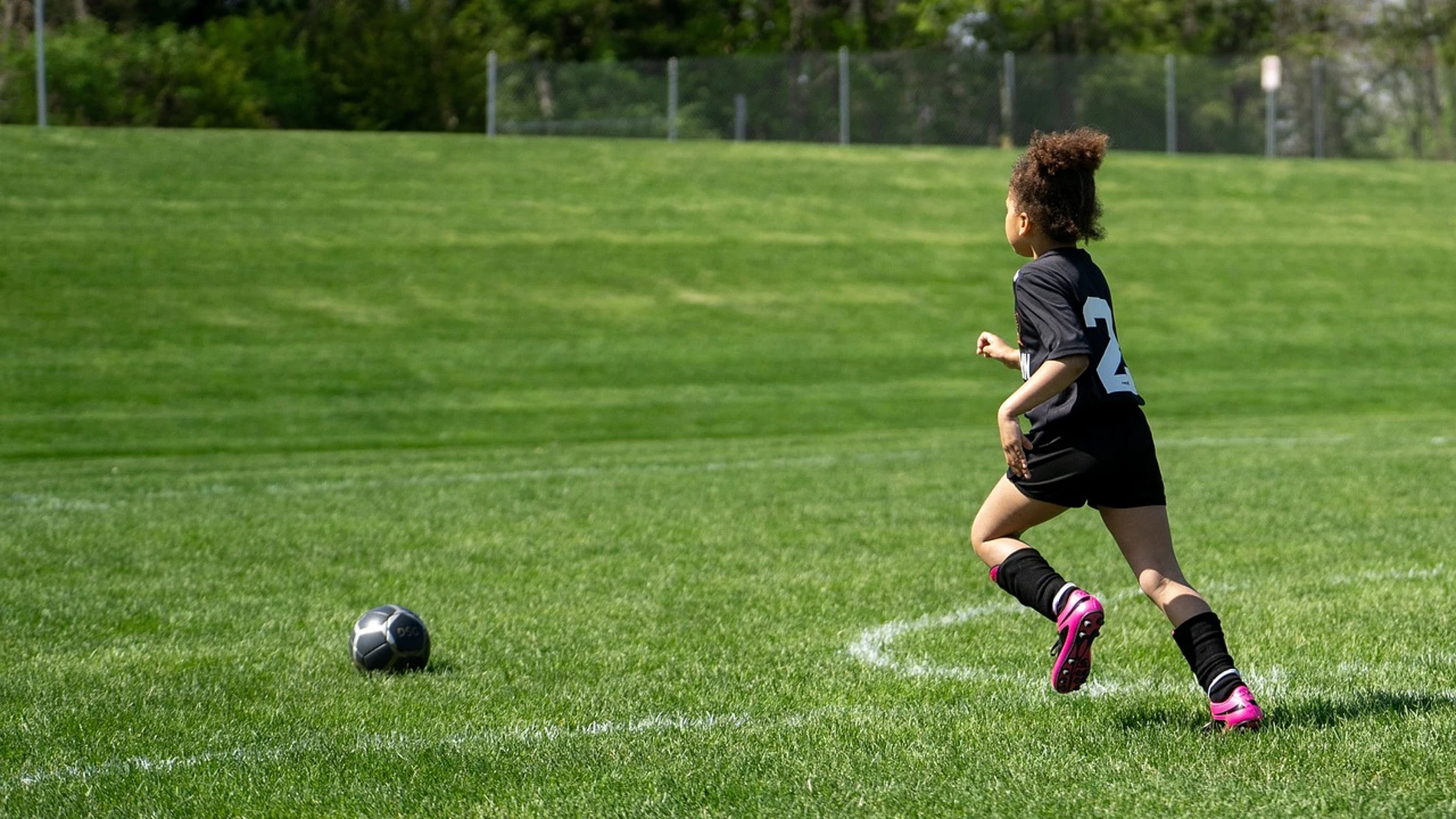 Imagen de archivo de un niño corriendo en un campo de fútbol