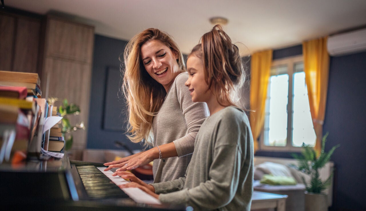 Una madre enseña a su hija a tocar el piano