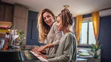 Una madre enseña a su hija a tocar el piano