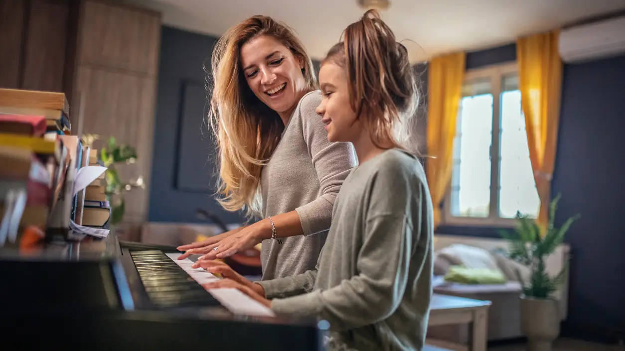 Una madre enseña a su hija a tocar el piano Una madre enseña a su hija a tocar el piano