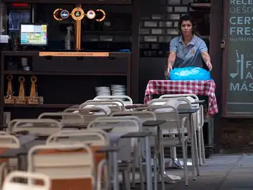 Una camarera coloca las mesa en un bar Una camarera coloca las mesa en un bar