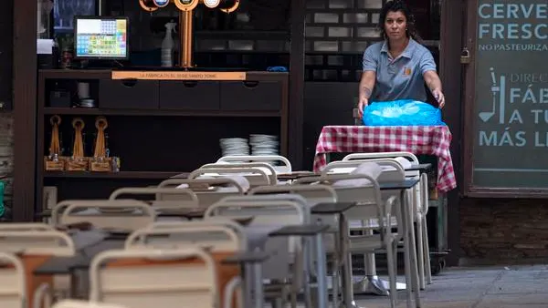 Una camarera coloca las mesa en un bar Una camarera coloca las mesa en un bar