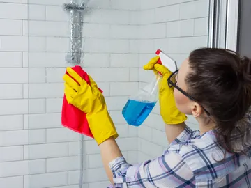 Persona limpiando la mampara de la ducha Persona limpiando la mampara de la ducha
