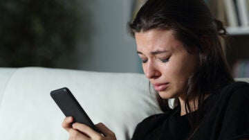 Una joven llorando al mirar el móvil