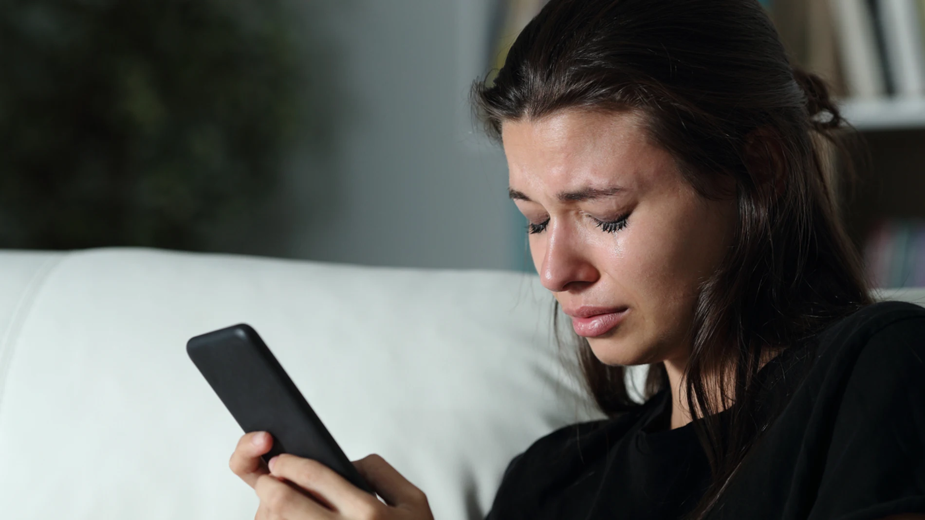 Una joven llorando al mirar el móvil