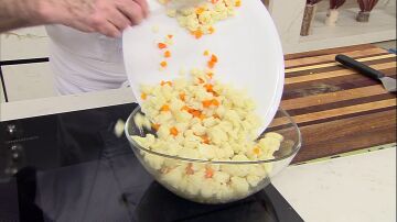 Añade la coliflor, las zanahorias, una pizca de sal y la mahonesa, y mezcla bien