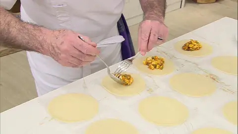 Extiende las empanadillas sobre la encimera, pon en el centro una porción de la farsa, dóblalas por la mitad y ciérralas presionando los bordes con un tenedor Extiende las empanadillas sobre la encimera, pon en el centro una porción de la farsa, dóblalas por la mitad y ciérralas presionando los bordes con un tenedor