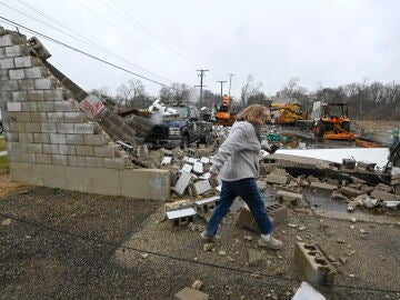 Una mujer pasa frente a un negocio destruido tras un tornado en Belvidere, Illinois, EEUU