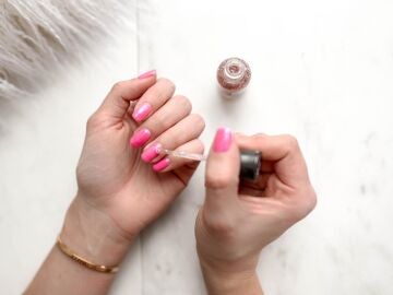 Persona se pinta las uñas de color rosa