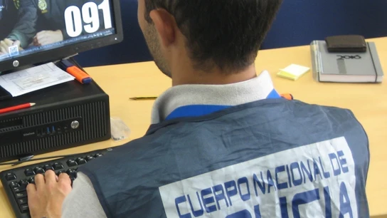 Un agente de la Policía investiga un ordenador Un agente de la Policía investiga un ordenador