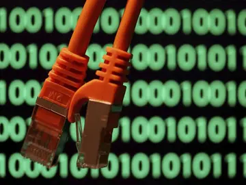 Imagen de archivo de unos cables sobre una pantalla de ordenador con un código binario Imagen de archivo de unos cables sobre una pantalla de ordenador con un código binario