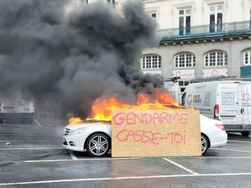 Un coche en llamas durante una protesta con una pancarta ardiendo durante las protestas contra la reforma de las pensiones en Rennes