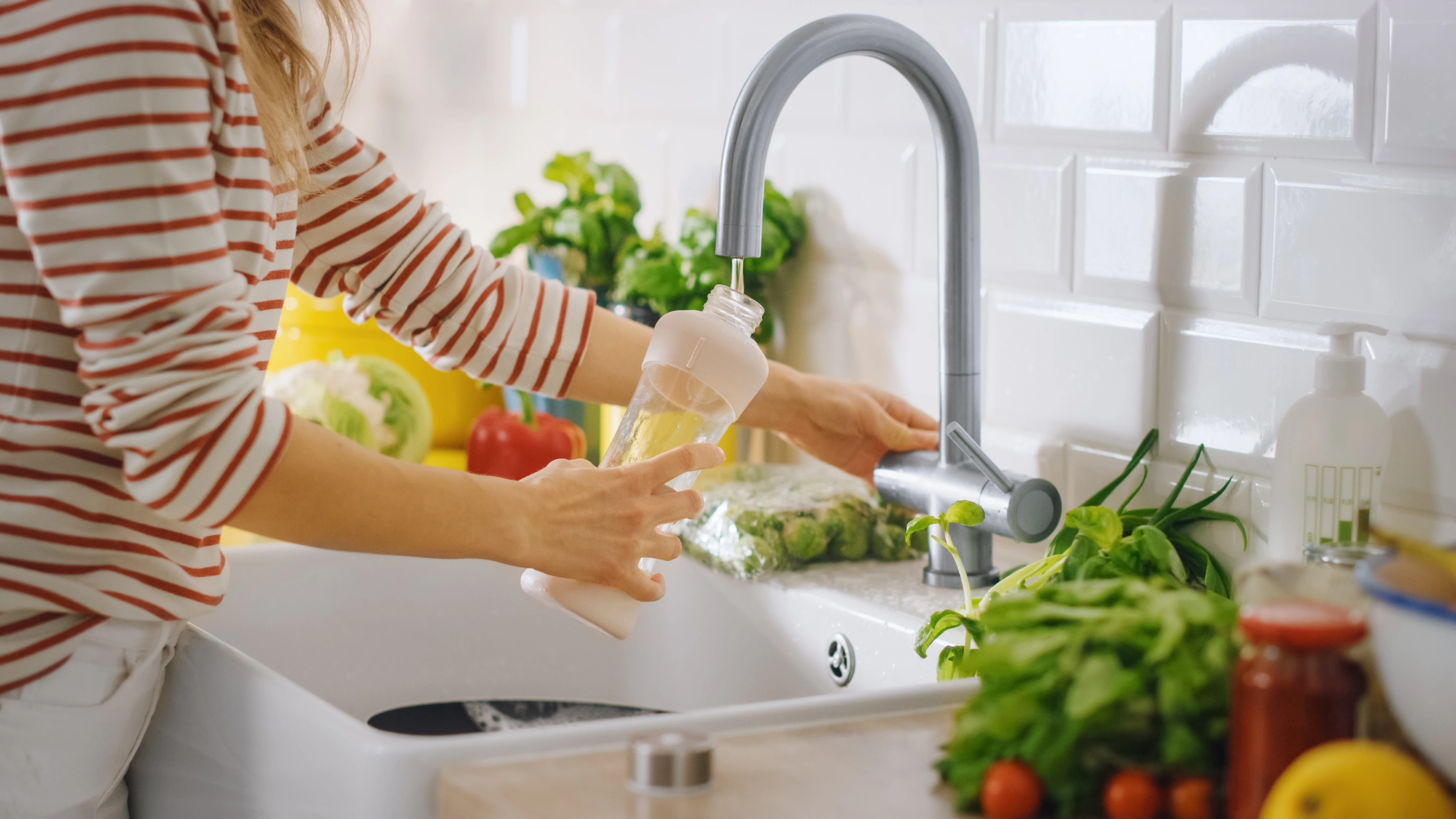 Mujer llenando una botella con agua del grifo
