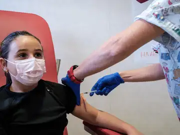 Personal sanitario vacunando a una niña Personal sanitario vacunando a una niña